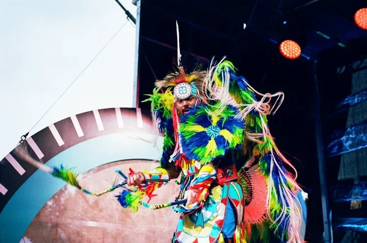 Powwow dancer in full regalia performing under stage lighting at a Winnipeg event