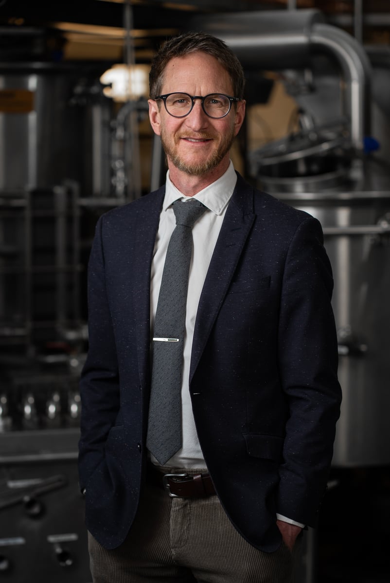 Environmental executive portrait of a man in a suit inside a production facility
