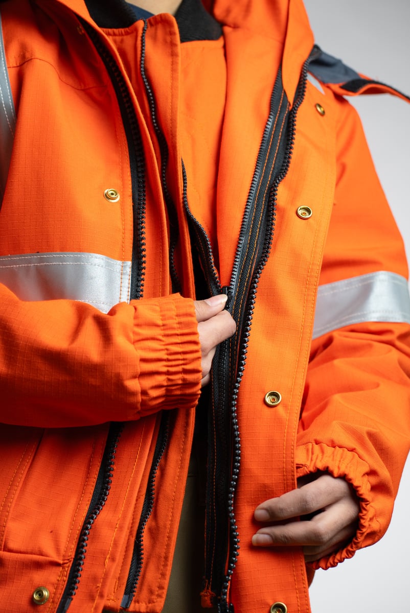 Product detail photograph of the cuff and zipper on an orange hi-vis work jacket